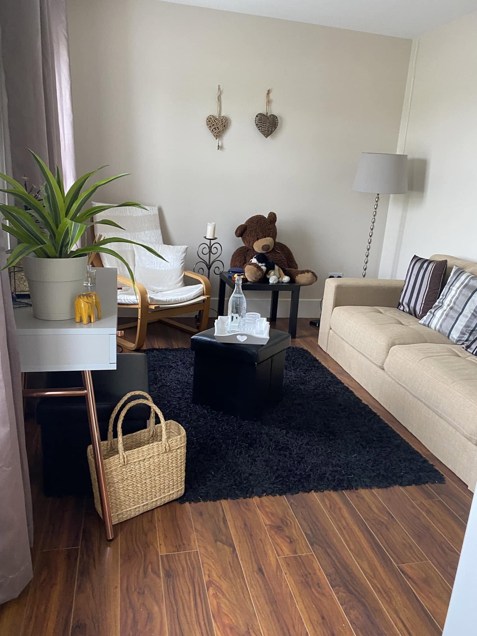 Light-filled room with a white armchair, beige sofa and a plant